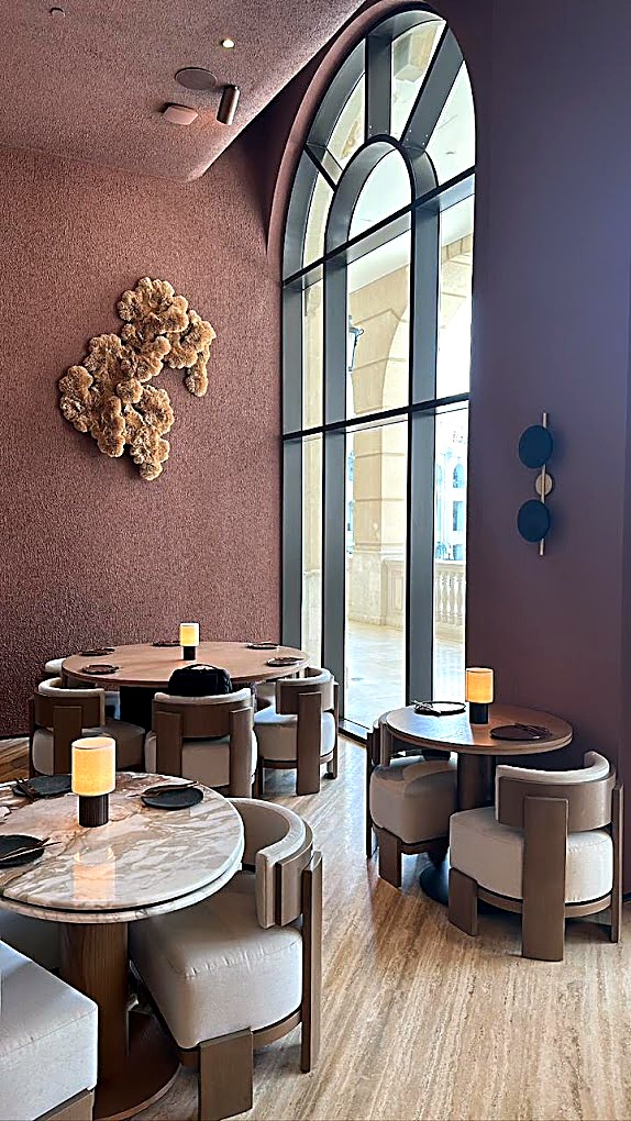 Lounge seating beside a tall arched window with a sculptural wall feature