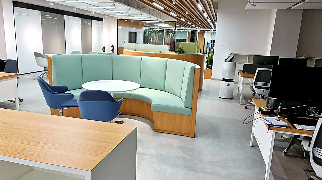 Curved green banquette and blue tub chairs beneath a timber slat ceiling