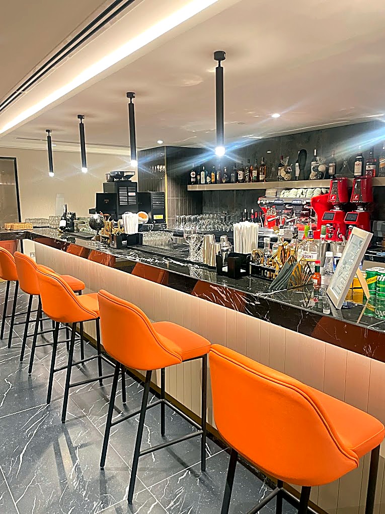 Long bar with orange leather stools and backlit shelving