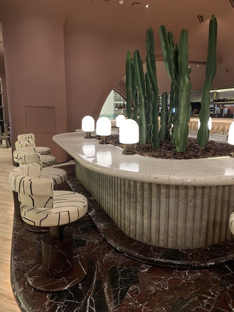 Curved stone-clad counter with a planted top and marble floor
