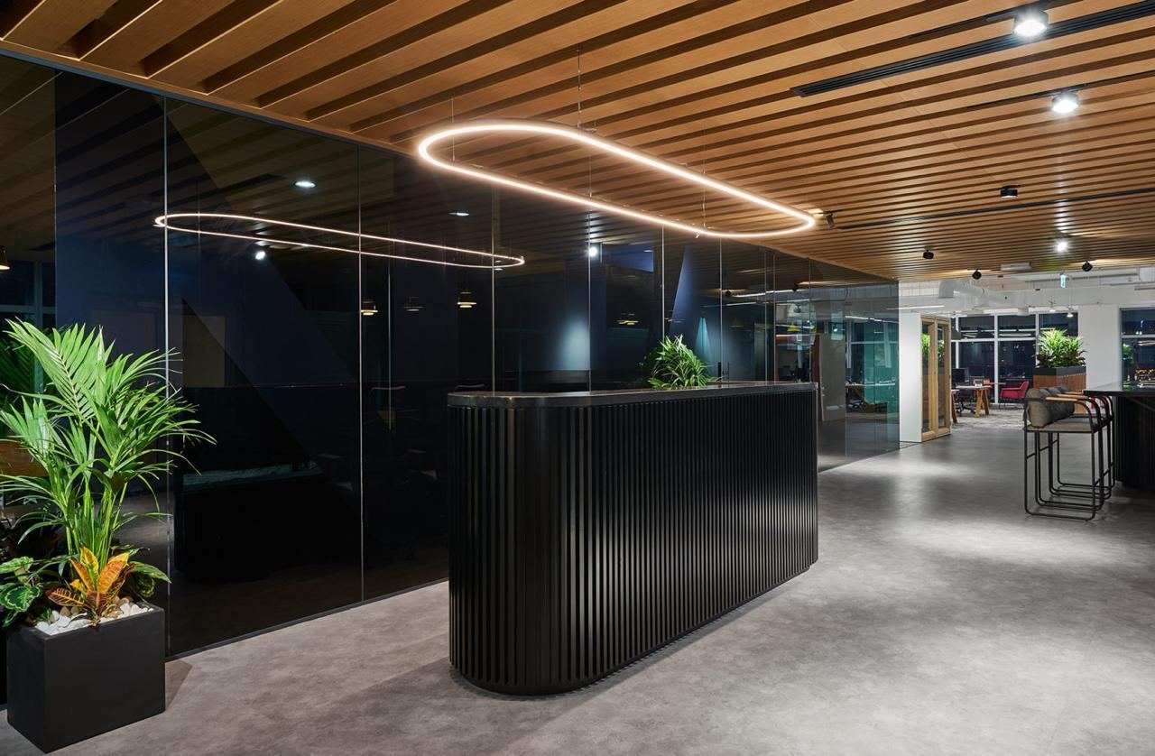 Reception with a fluted black desk under a slatted timber ceiling, at handover